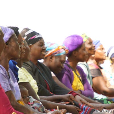A row of African women watching something and smiling