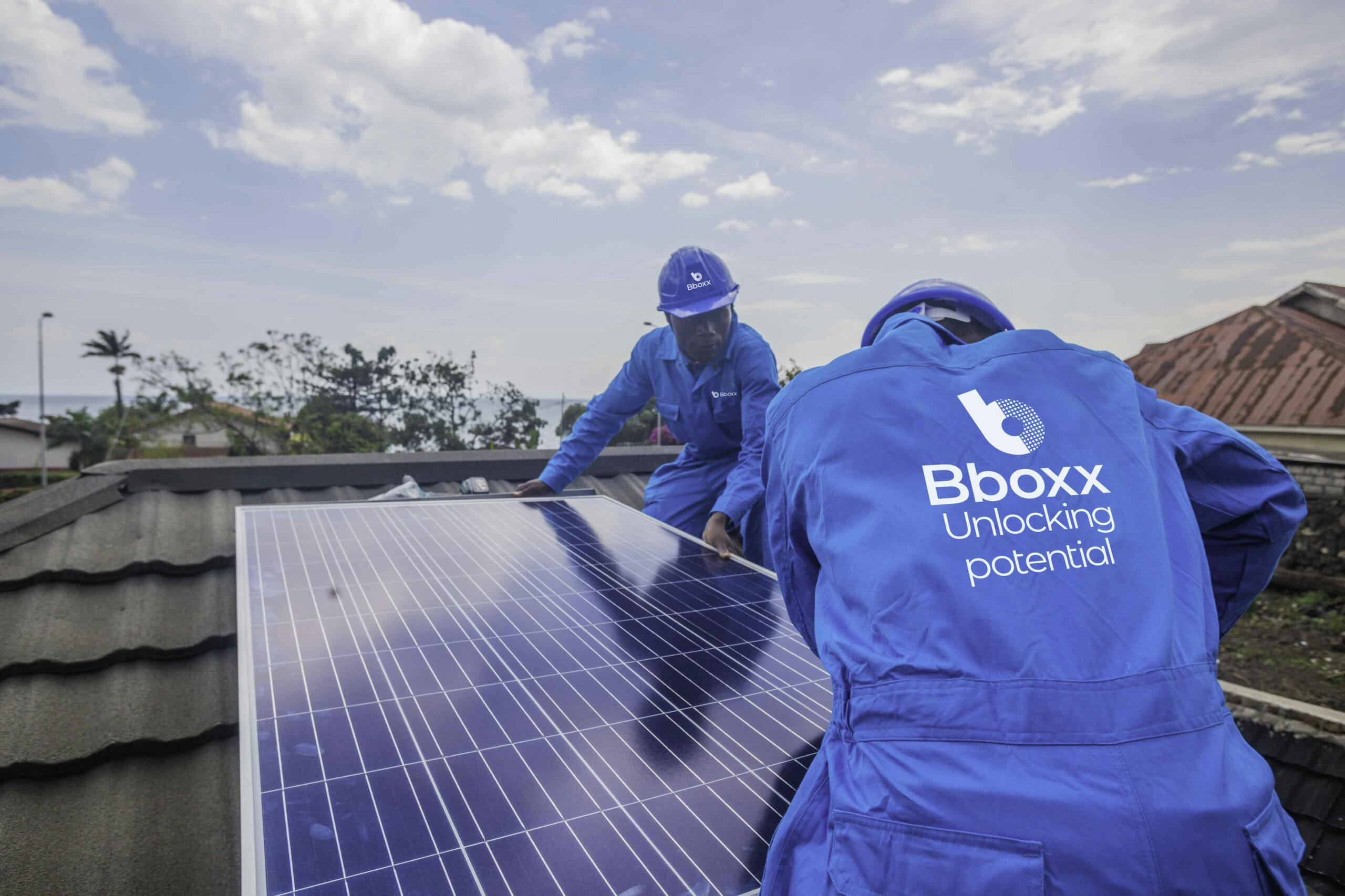 Two Engineers in PPE branded Bboxx working on solar panels