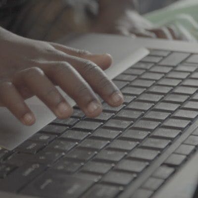 close-up of child's hand hovering over laptop keyboard