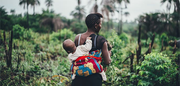 Woman carrying child through forest